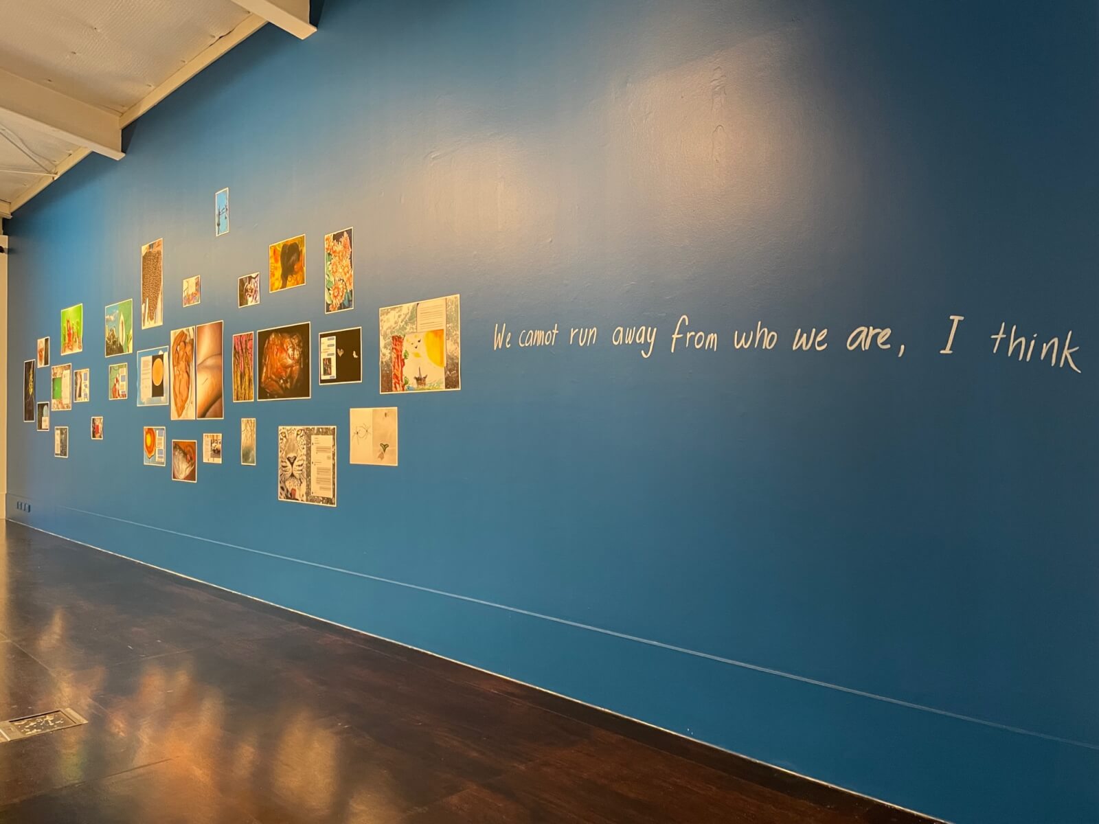 A blue wall with art of photographer Shwe Wutt Hmon and the words We cannot run away from who we are