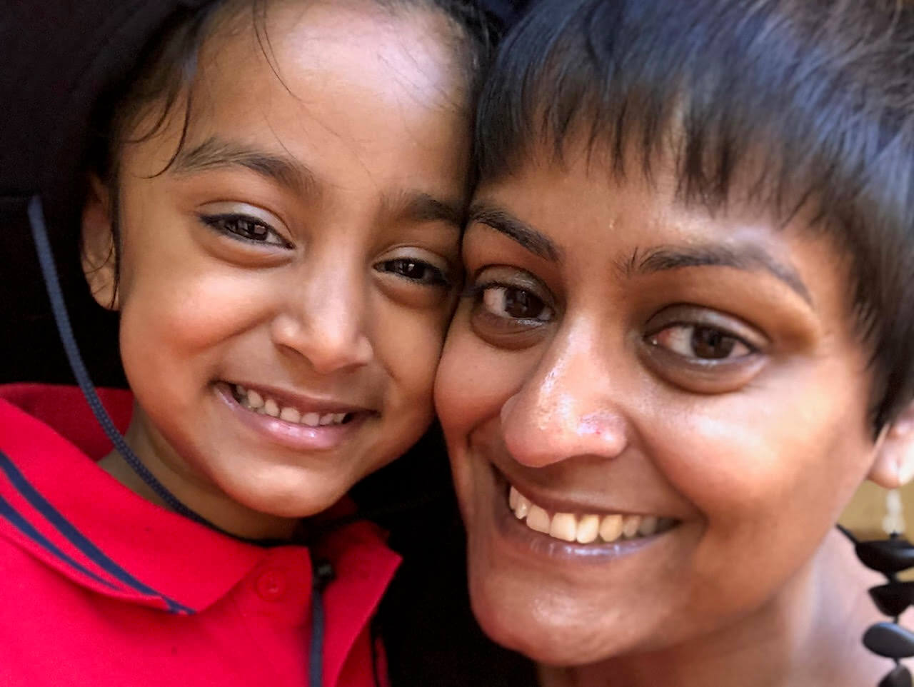 An image of a mother and her daughter, smiling as they look at the camera