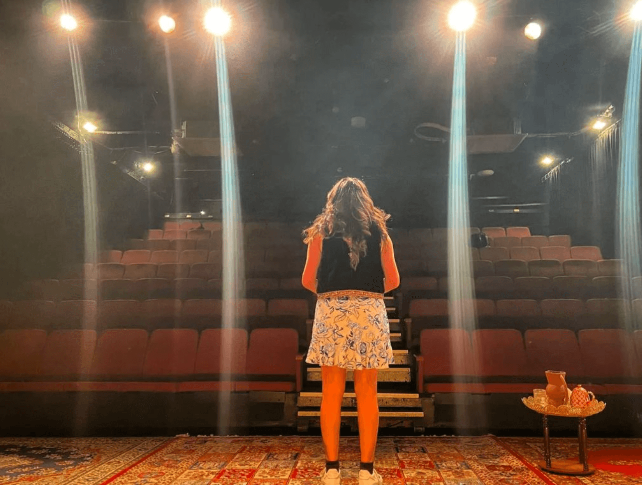 Writer Almitra Mavalvala stands in front of lights and an empty theatre during rehearsal.